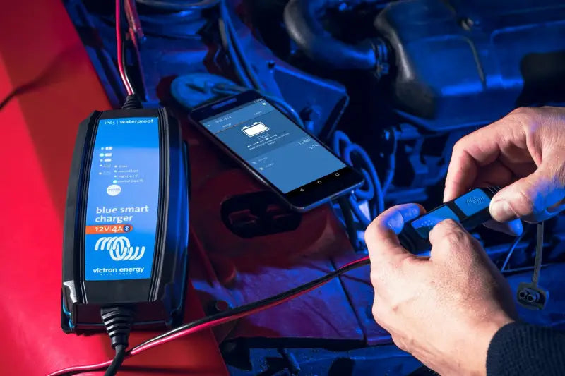 Man using iPhone with Blue Smart IP65 Charger app to check lithium battery status