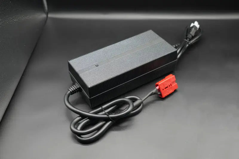 12V 20A lithium battery charger with black car battery and red power cord.