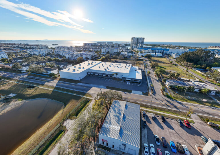 Exterior view of the new Lithium Battery Company factory located at 5201 S Westshore Blvd, Tampa, FL 33611. The modern facility features sleek architecture and expansive windows, surrounded by landscaped greenery under a clear blue sky.